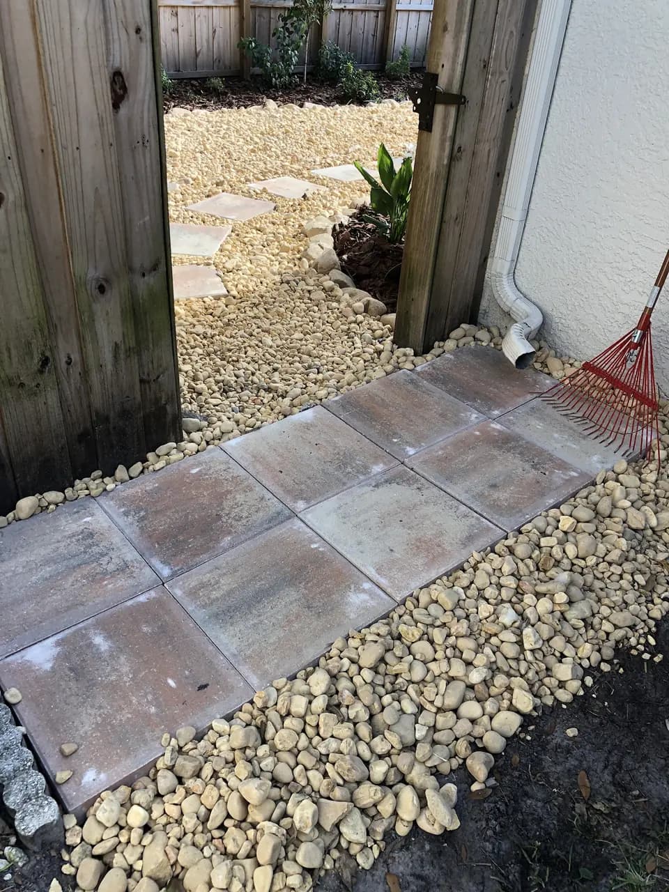 Paver pad and river rock beside a wooden gate