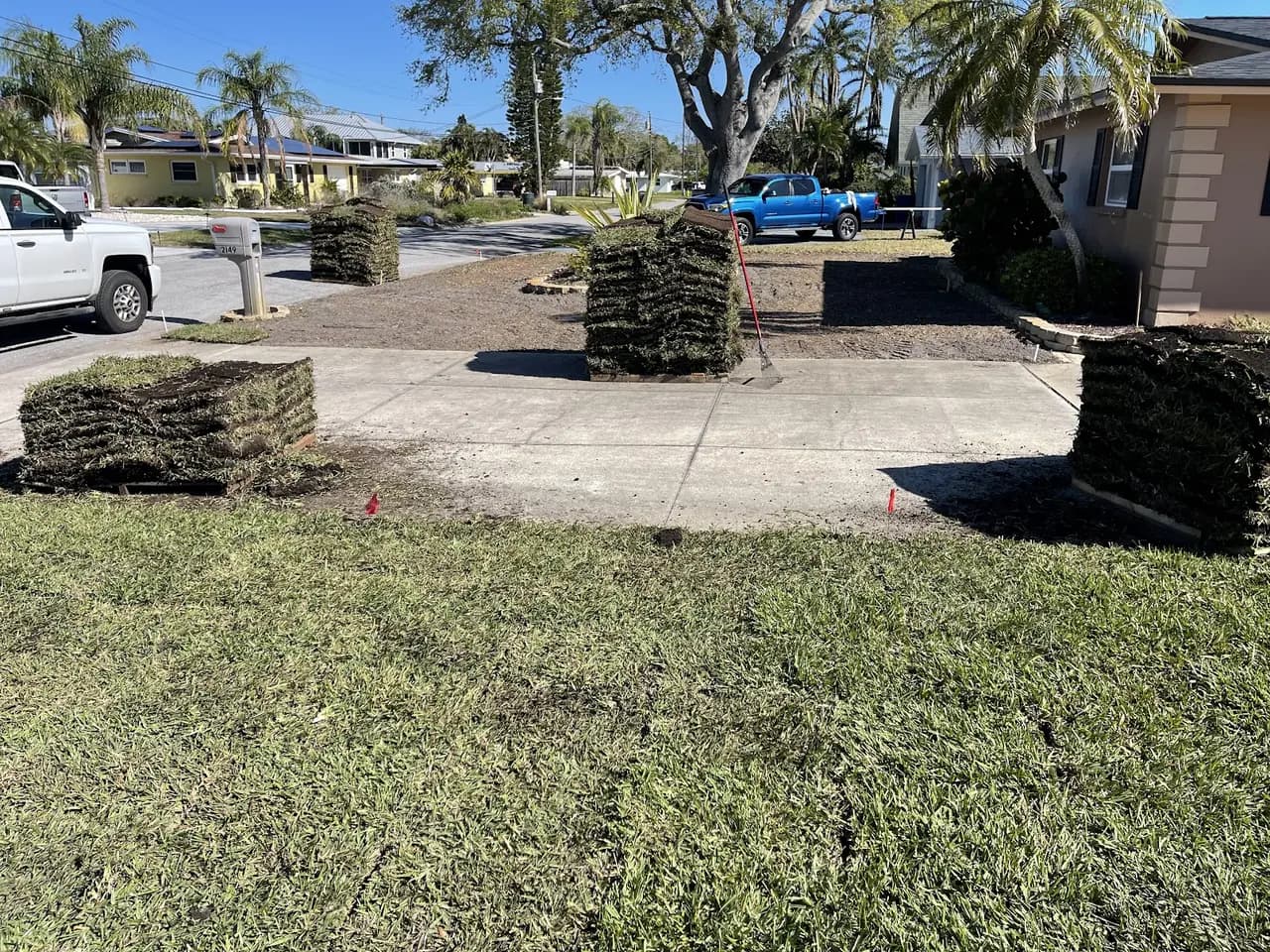 Fresh sod laid in a front yard with rolls stacked on the driveway