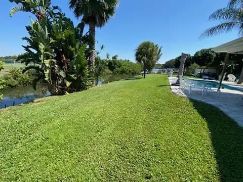 Mowed waterfront lawn running down to a canal beside a pool